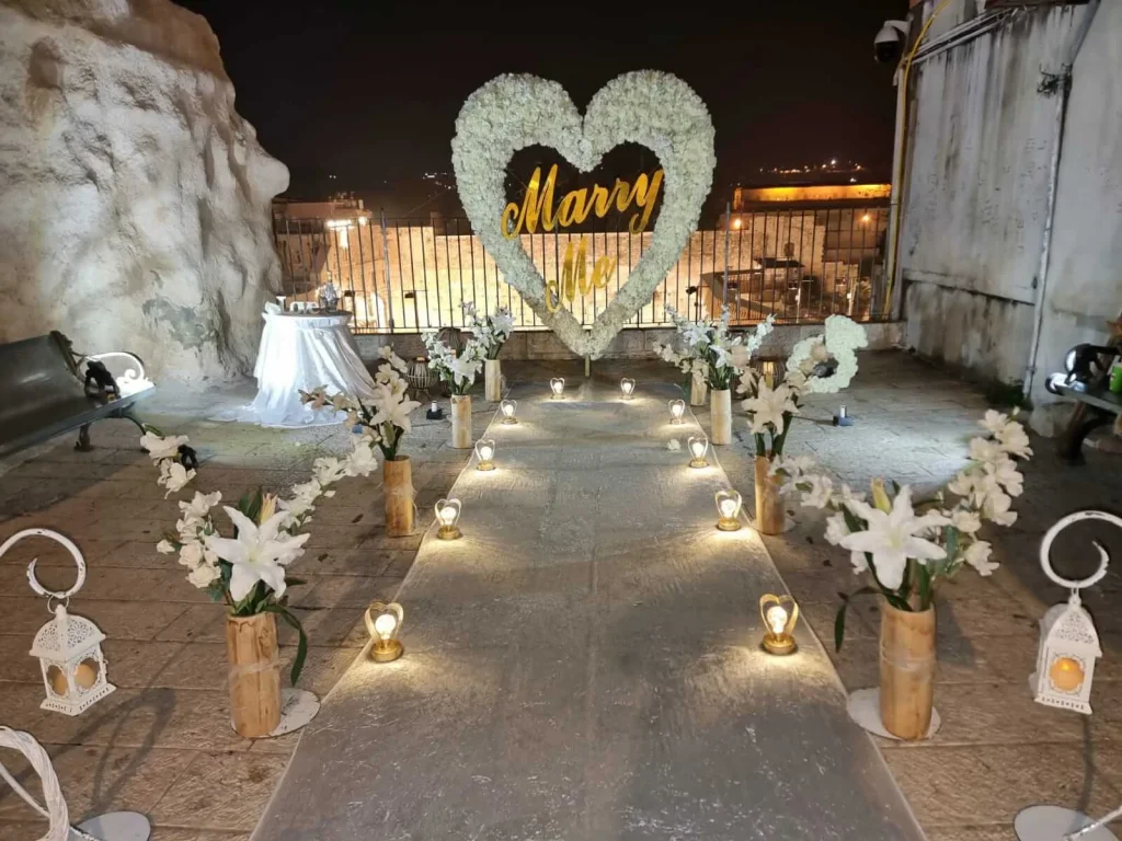 Cœur de fleurs blanches et allée de lanternes sur une terrasse en pierre face à la Vieille Ville, de nuit